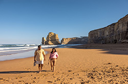 Two people stroll along the sandy beach at Gibsons Steps, located on the iconic Great Ocean Road, VIC © Tourism Australia