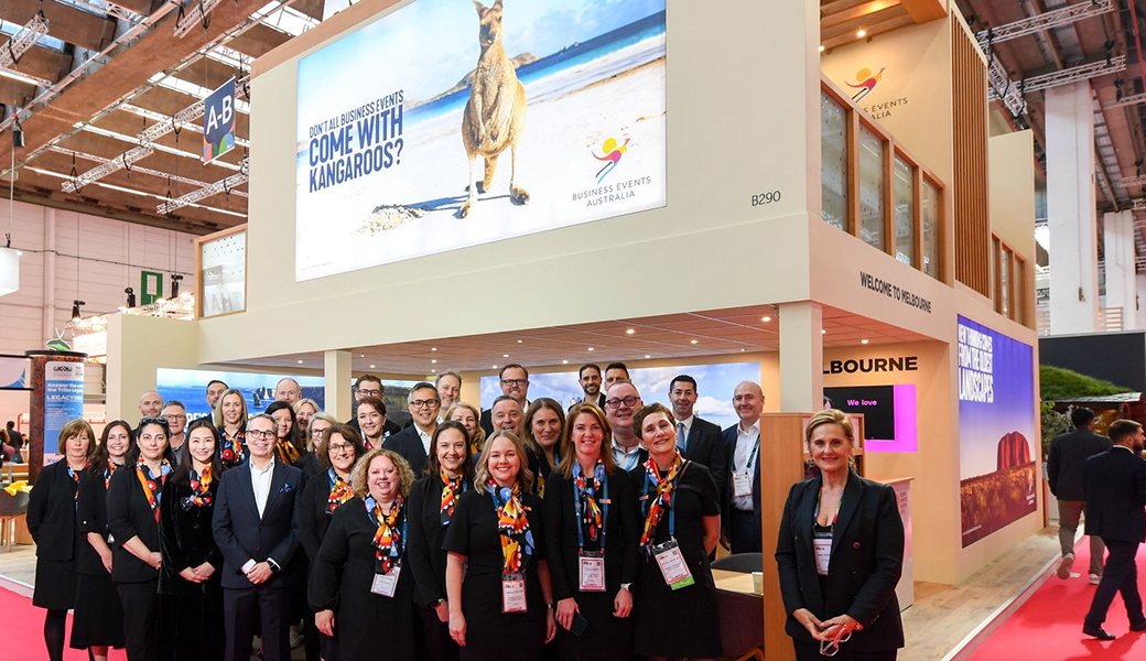 Australian industry standing for a group photo at the Australia stand with imagery of a kangaroo above them.