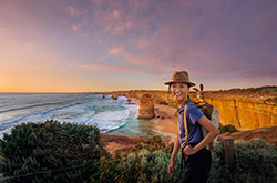 A woman admires the Twelve Apostles coastline at sunset.
