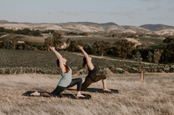 Two women in a field doing yoga poses, Barossa Valley, South Australia