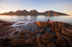 A person sits on the rocks at of Coles Bay in Freycinet National Park, TAS © Tourism Australia