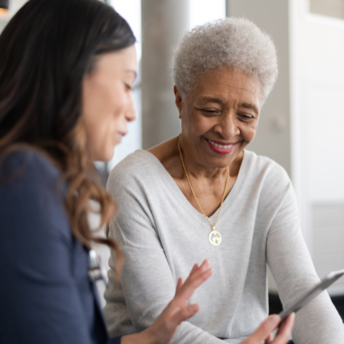 Care provider with older Australian smiling and looking at digital device,