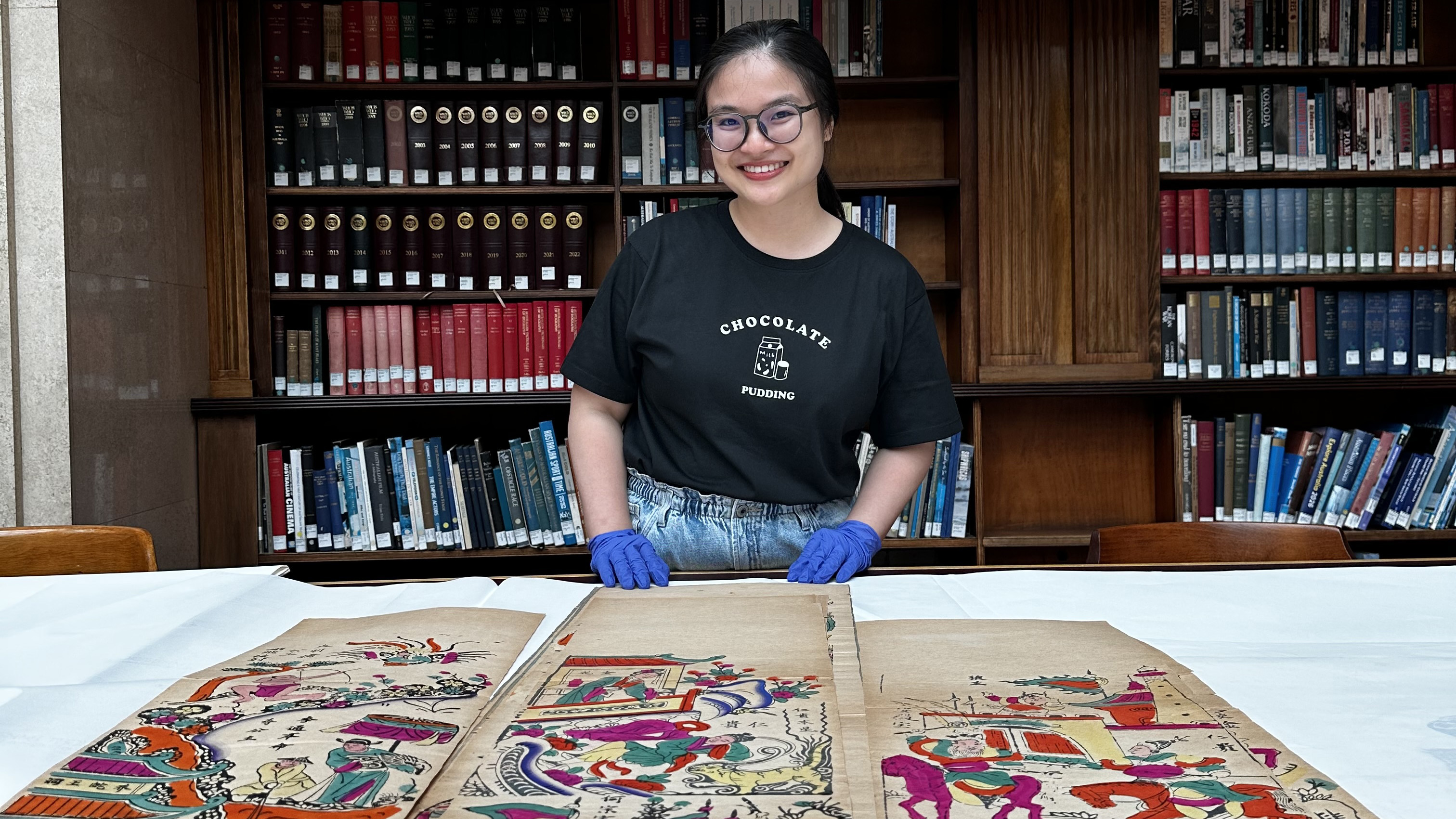 A woman smiling with items from a library collection