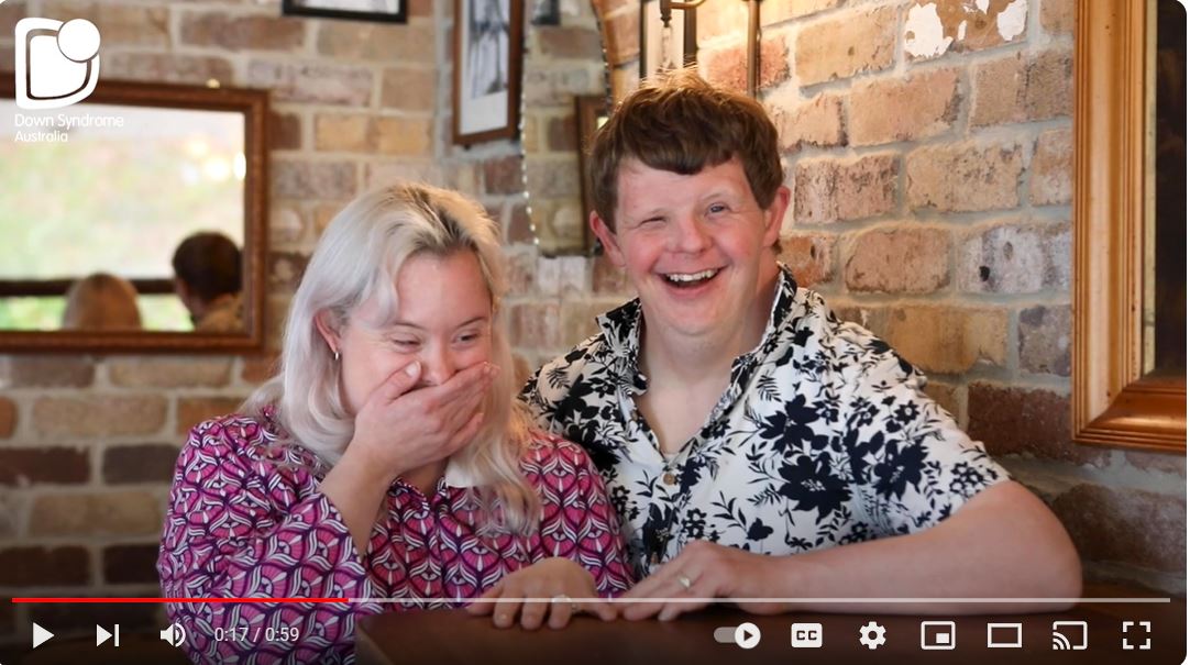 This is a photo of a male and female with Down syndrome smiling.