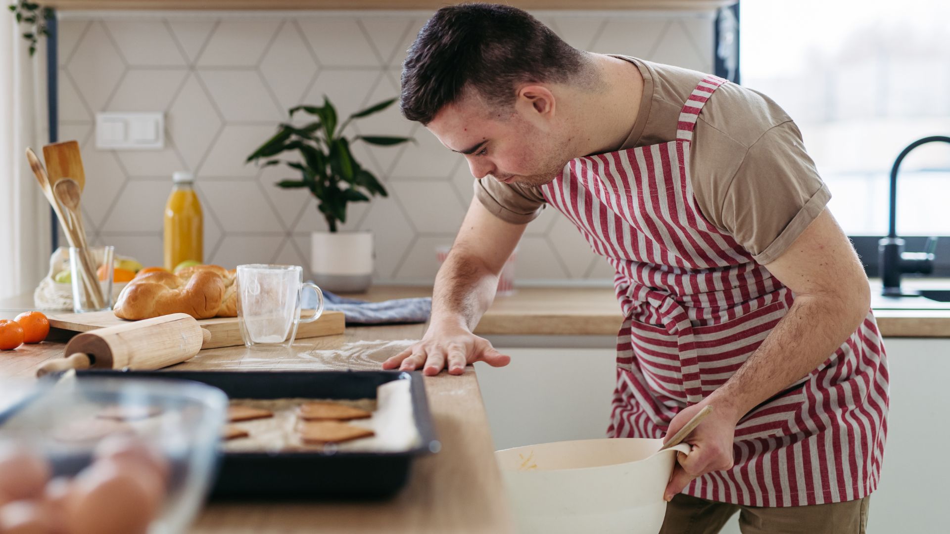 This is a photo of a young man with Down syndrome baking cookies in a kitchen