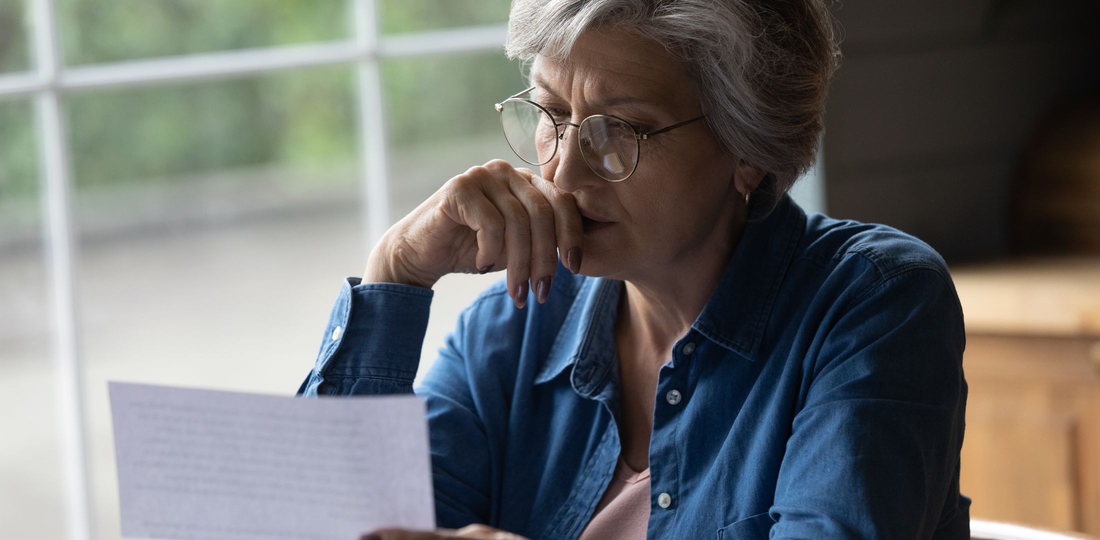 This is a photo of an older female reading a letter