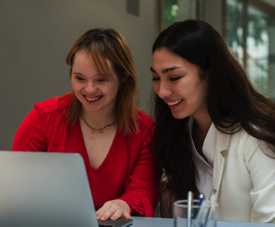 two women look at a computer screen together