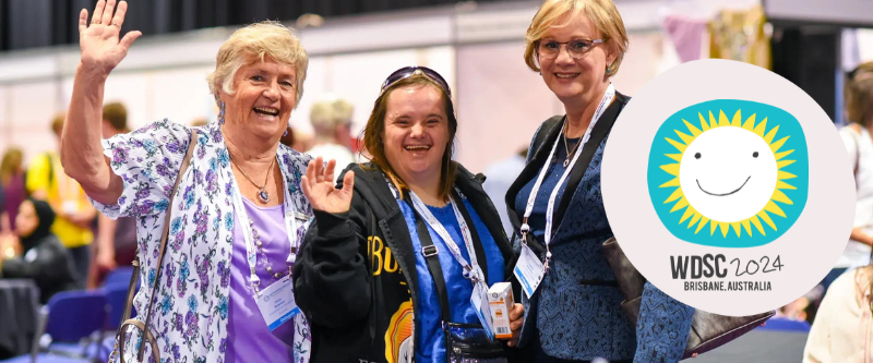 This is a photo of three females smiling at the camera. One has Down syndrome. It also includes a logo for World Down Syndrome Congress 2024 in Brisbane, Australia.