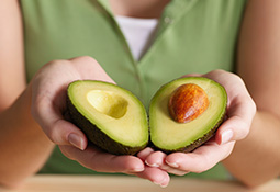 Woman holding halved avocado