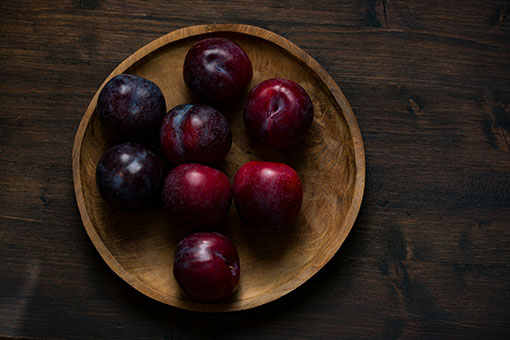 Bowl of plums on a wooden table