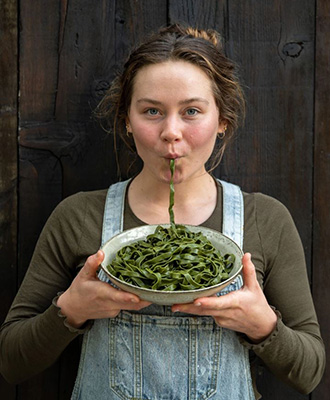 Young woman eating seaweed pasta