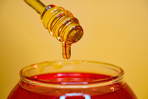 Honey dripping into a jar