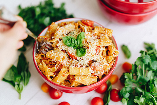 Person eating Roma Foods pasta in a bowl