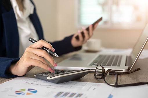 Business woman using calculator with laptop