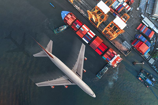 Aeroplane flying over a cargo ship in port