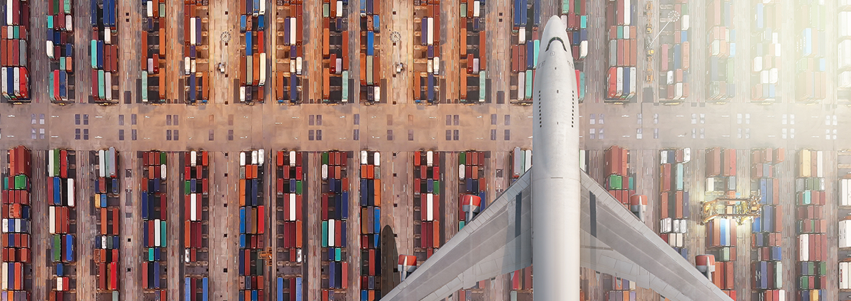 Cargo plane flying over shipping containers at port