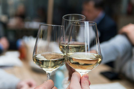 People clinking glasses of white wine